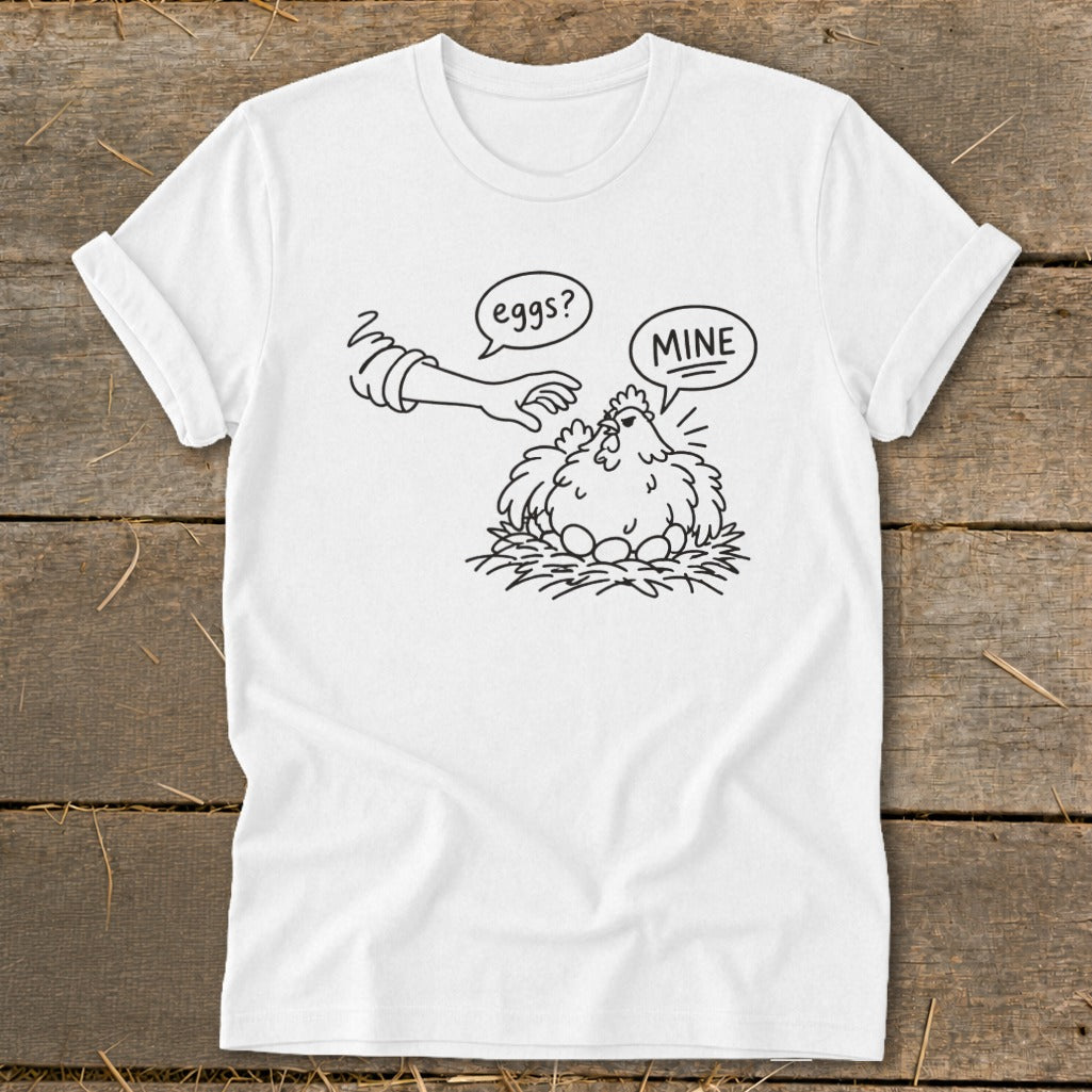 White t-shirt with a black line drawing of a hen protecting eggs, saying "MINE".
