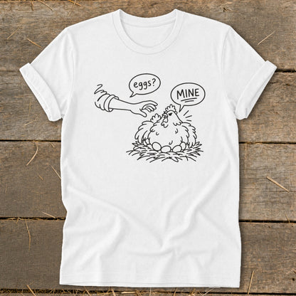 White t-shirt with a black line drawing of a hen protecting eggs, saying "MINE".