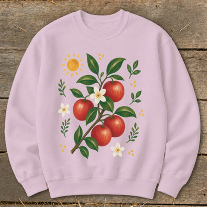 Pink sweatshirt with a painted illustration of an apple branch, flowers, and sun.