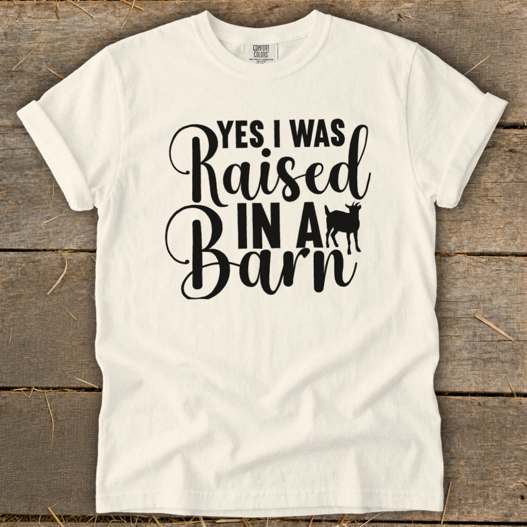 Cream t-shirt with black text "YES I WAS Raised IN A Barn" and a goat silhouette.