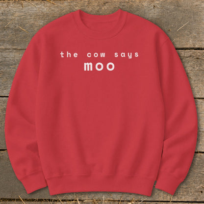 Red sweatshirt with white text "the cow says moo" on a wooden background.