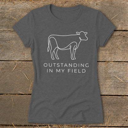 Dark grey t-shirt with white line art cow and text "OUTSTANDING IN MY FIELD".