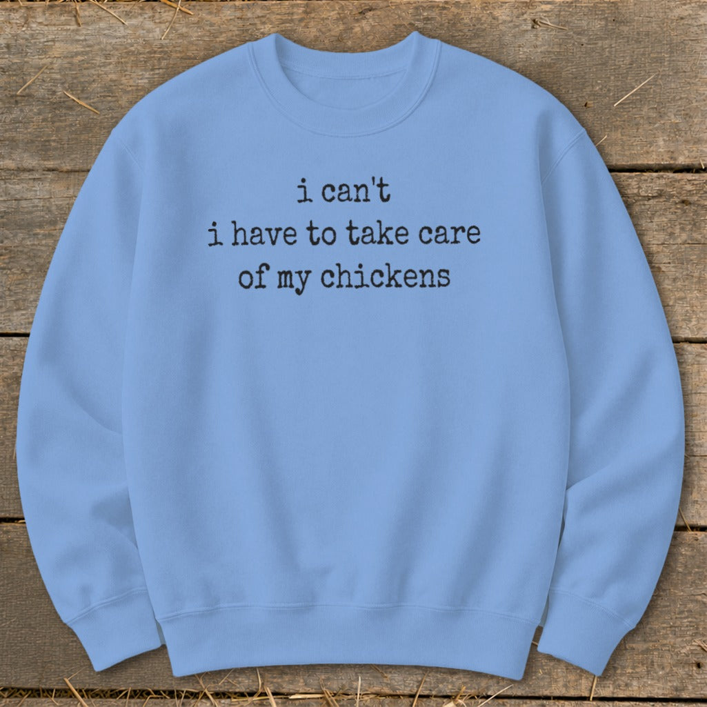 Light blue sweatshirt with black text reading "i can't i have to take care of my chickens".