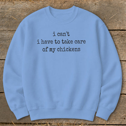 Light blue sweatshirt with black text reading "i can't i have to take care of my chickens".
