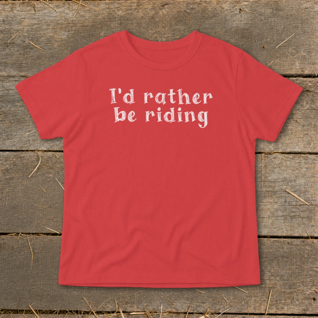 Red t-shirt with white text "I'd rather be riding" on rustic wooden planks.