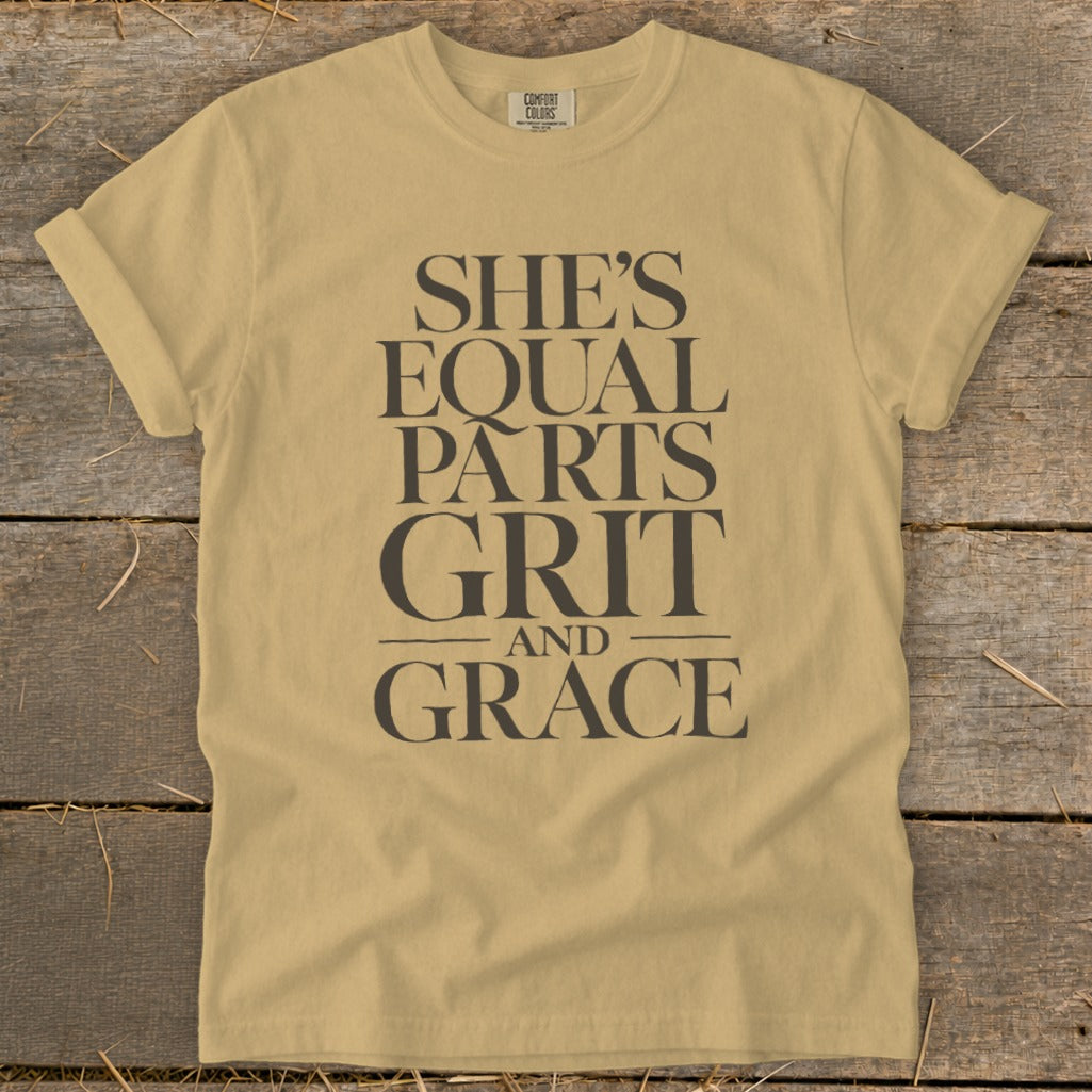 Tan Comfort Colors t-shirt with "She's Equal Parts Grit and Grace" printed in dark grey text.