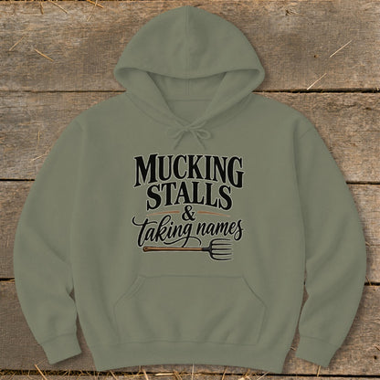 Olive green hoodie with text "MUCKING STALLS & taking names" and a pitchfork.