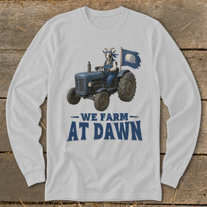 White long-sleeve shirt with a goat driving a blue tractor and flag, reads "We Farm At Dawn."