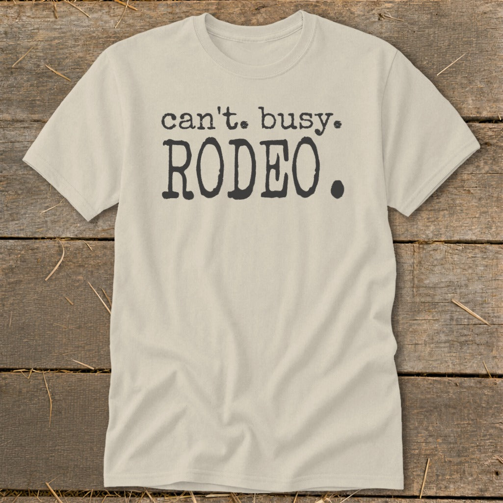 Light tan t-shirt with "can't. busy. RODEO." printed in dark gray.