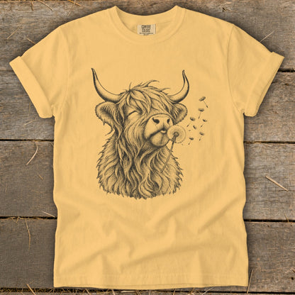 Yellow t-shirt with a line drawing of a Highland cow blowing a dandelion.