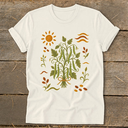 Cream t-shirt with a central bouquet of pea pods, leaves, and flowers, surrounded by decorative elements.