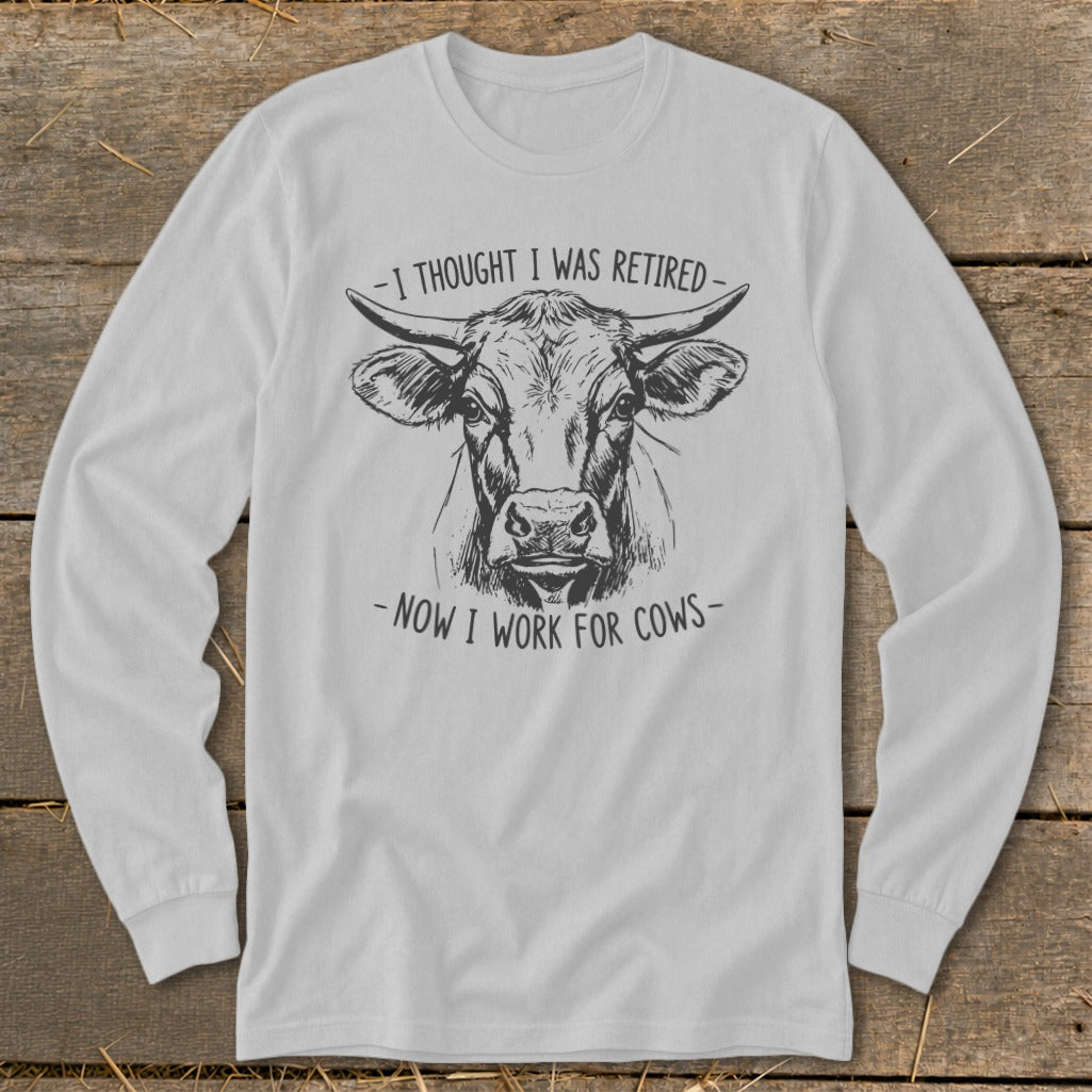 Light gray long-sleeve shirt with a sketch of a cow and text "I thought I was retired - now I work for cows".