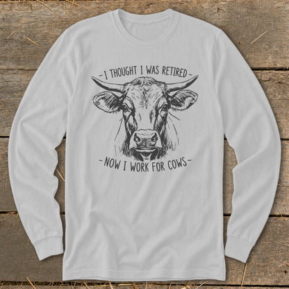 Light gray long-sleeve shirt with a sketch of a cow and text "I thought I was retired - now I work for cows".