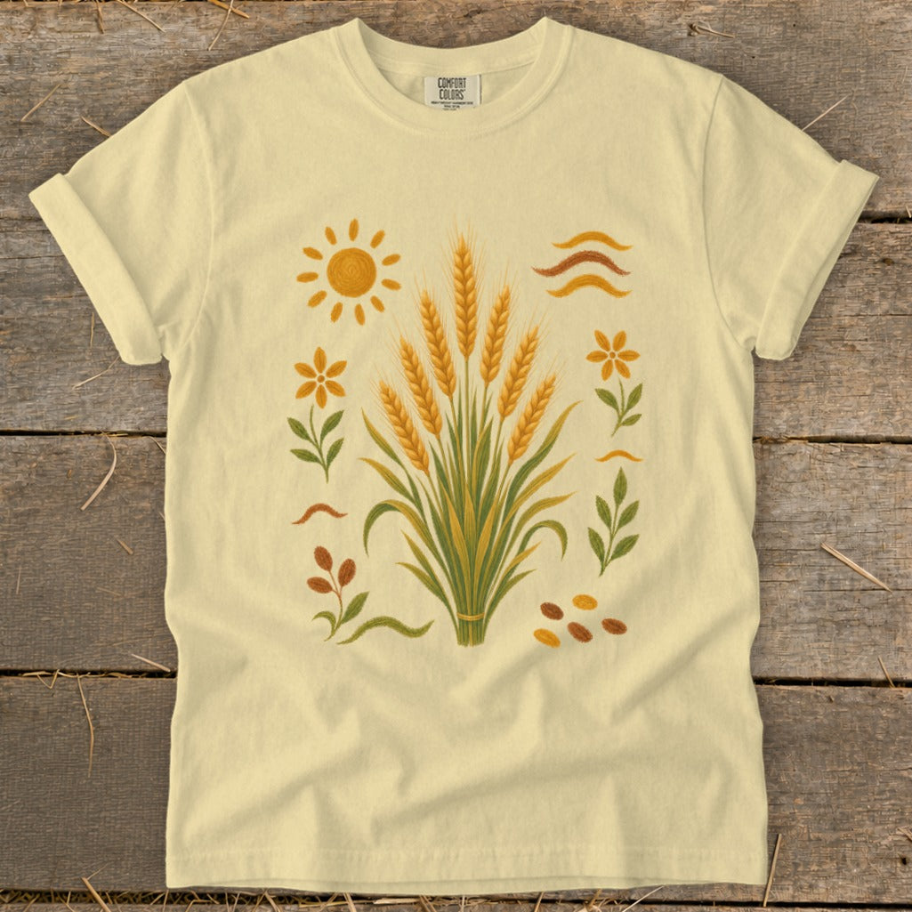 Yellow t-shirt with wheat stalks, sun, flowers, and abstract lines design.