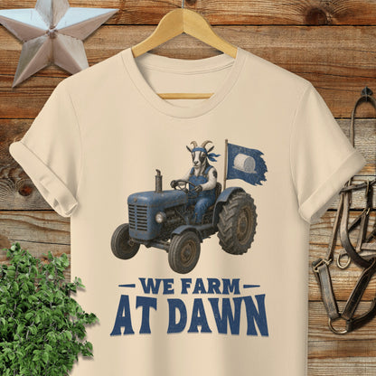 Cream t-shirt with cartoon goat driving tractor, "We Farm At Dawn" text.
