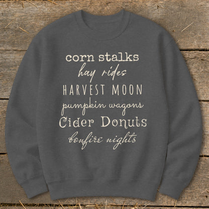Gray sweatshirt with white text listing "corn stalks, hay rides, harvest moon, pumpkin wagons, Cider Donuts, bonfire nights."