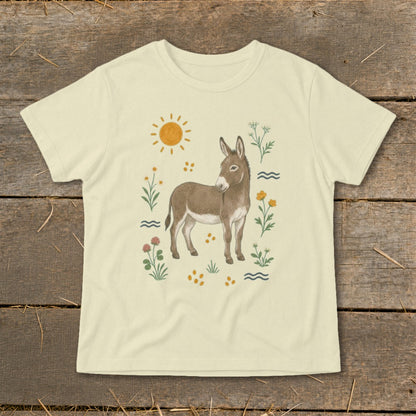 Light yellow t-shirt with a drawing of a donkey surrounded by flowers, sun, and wavy lines.