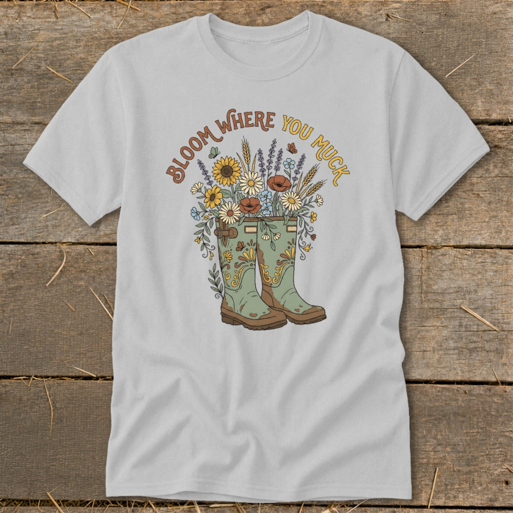 T-shirt with green boots overflowing with flowers and text "Bloom Where You Muck."