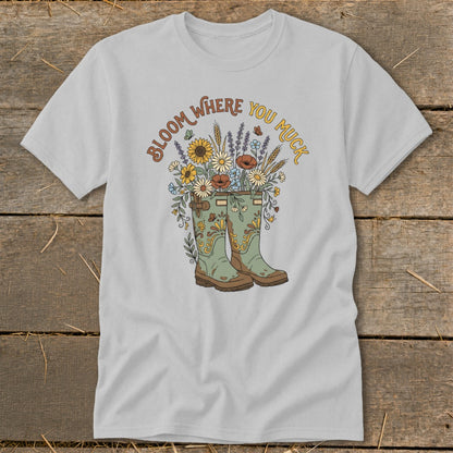T-shirt with green boots overflowing with flowers and text "Bloom Where You Muck."