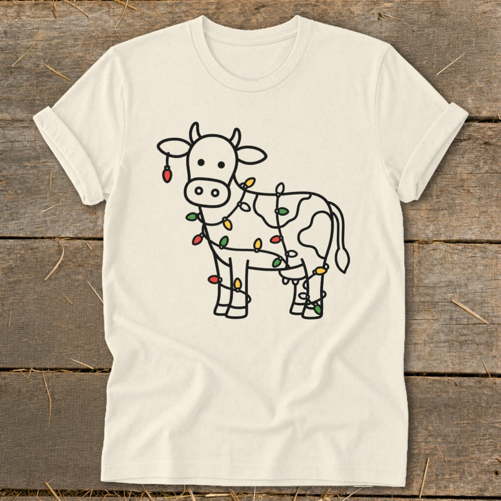 Cream t-shirt with outline of cow wrapped in colorful Christmas lights.