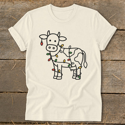 Cream t-shirt with outline of cow wrapped in colorful Christmas lights.