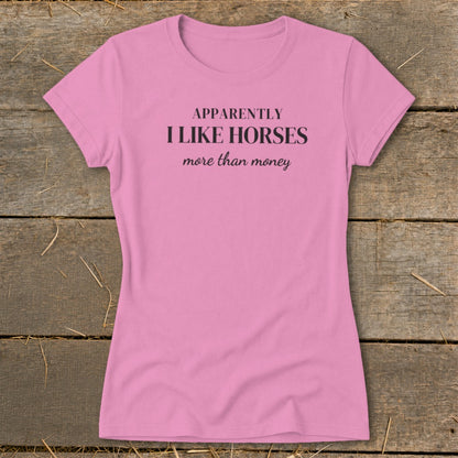 Pink t-shirt with black text that reads "APPARENTLY I LIKE HORSES more than money".