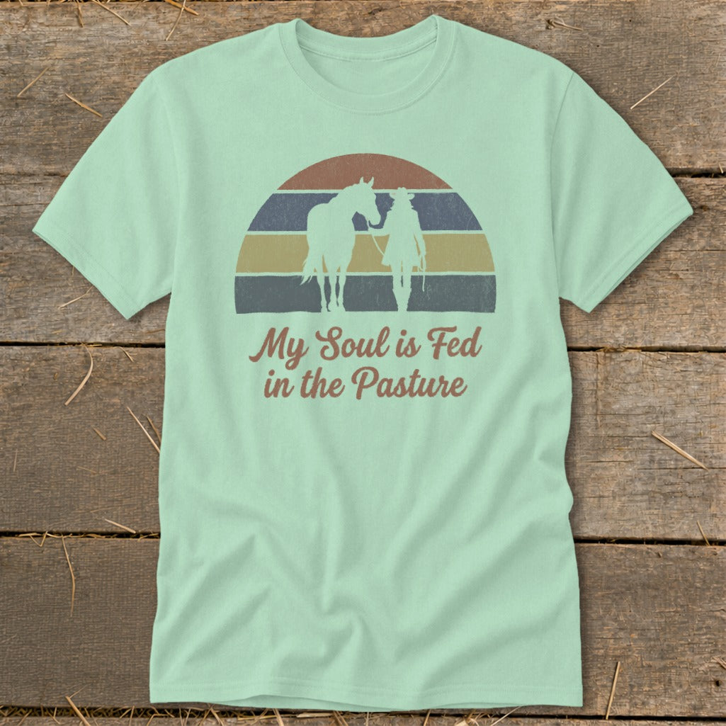 Light teal t-shirt with "My Soul is Fed in the Pasture" text and cowboy with horse graphic.