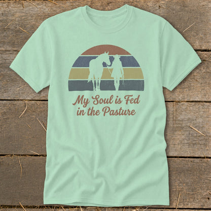 Light teal t-shirt with "My Soul is Fed in the Pasture" text and cowboy with horse graphic.