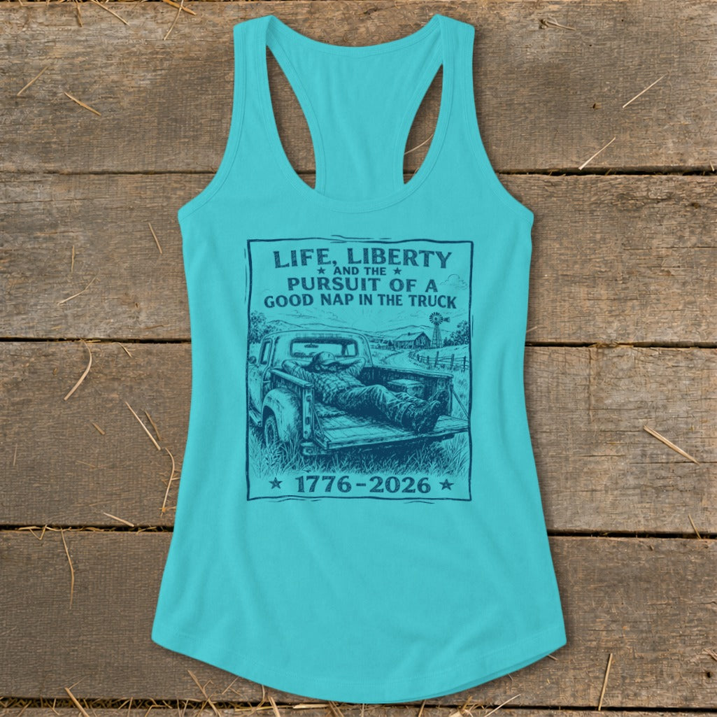 Turquoise tank top with graphic of man sleeping in truck bed. Text reads "Life, Liberty and the Pursuit of a Good Nap in the Truck 1776-2026".