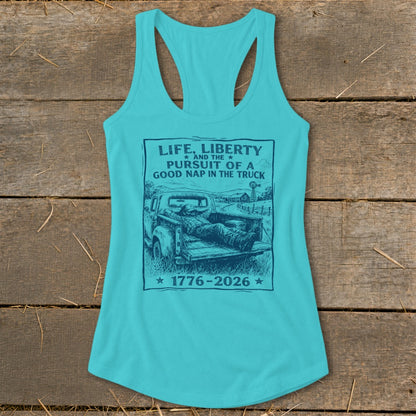 Turquoise tank top with graphic of man sleeping in truck bed. Text reads "Life, Liberty and the Pursuit of a Good Nap in the Truck 1776-2026".