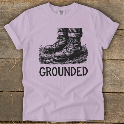 T-shirt with black ink drawing of boots in grass and the word "GROUNDED".