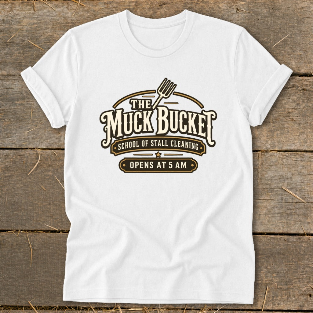 White t-shirt with "The Muck Bucket School of Stall Cleaning Opens at 5 AM" graphic.