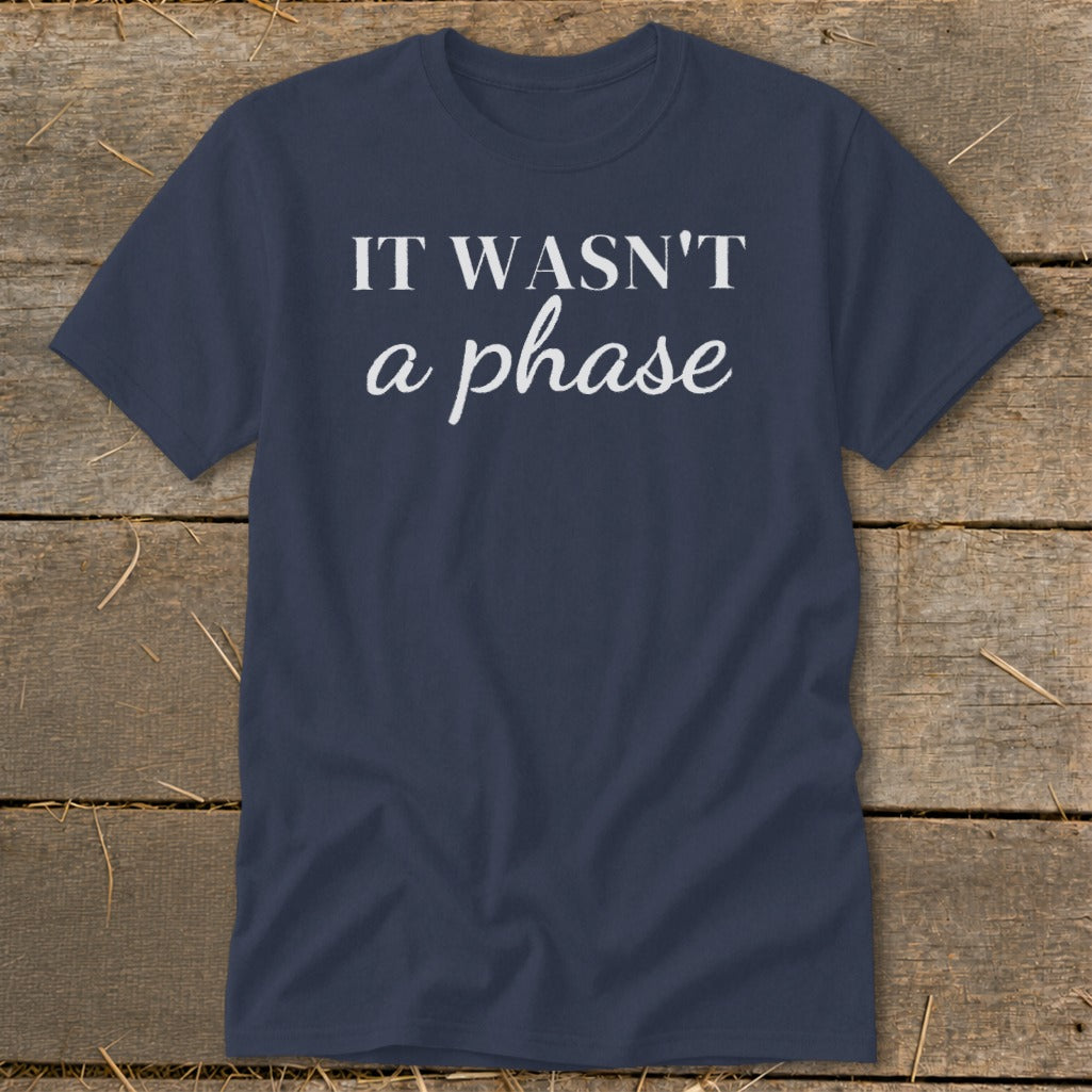 Navy t-shirt with white text "IT WASN'T a phase" on a wooden background.