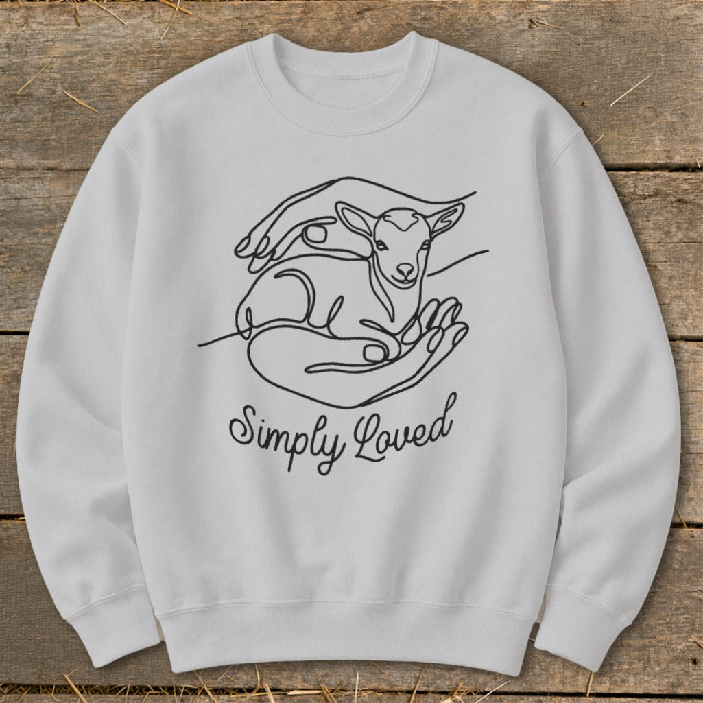 White sweatshirt with line art of a lamb cradled in hands and the text "Simply Loved".