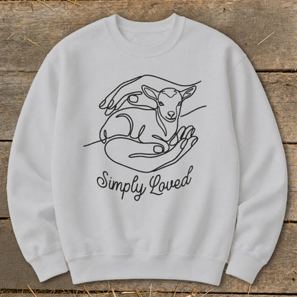 White sweatshirt with line art of a lamb cradled in hands and the text "Simply Loved".