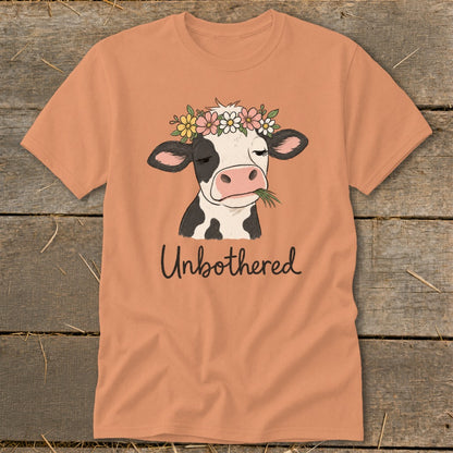 T-shirt with a cow wearing a flower crown and eating grass, text reads "Unbothered".