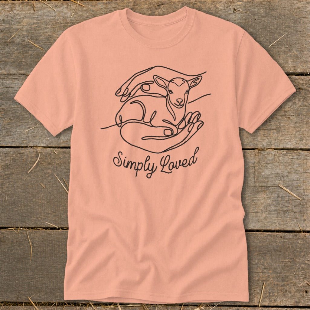 Peach t-shirt with minimalist line art of hands cradling a lamb and "Simply Loved" text.