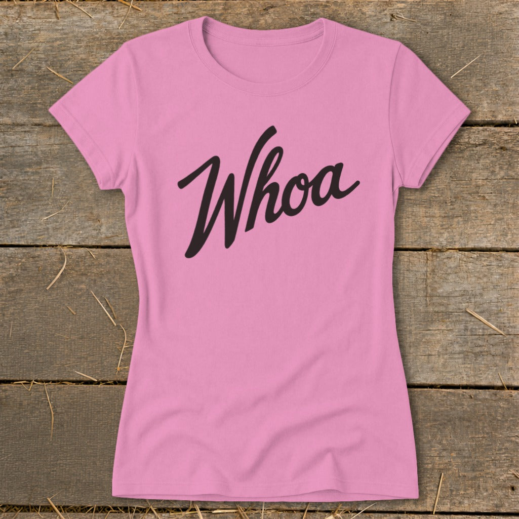 Pink t-shirt with black "Whoa" text on a wooden background.
