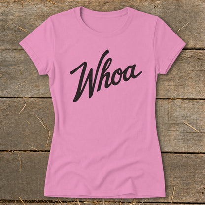 Pink t-shirt with black "Whoa" text on a wooden background.