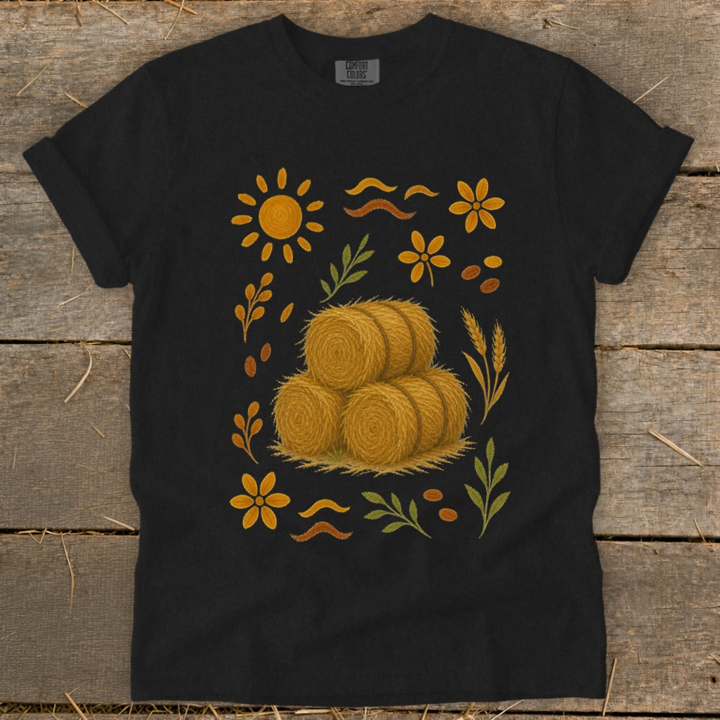 Black t-shirt with stacked hay bales and fall-themed graphic elements.