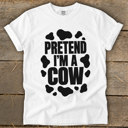 White t-shirt with black text "Pretend I'm a Cow" and cow spots.