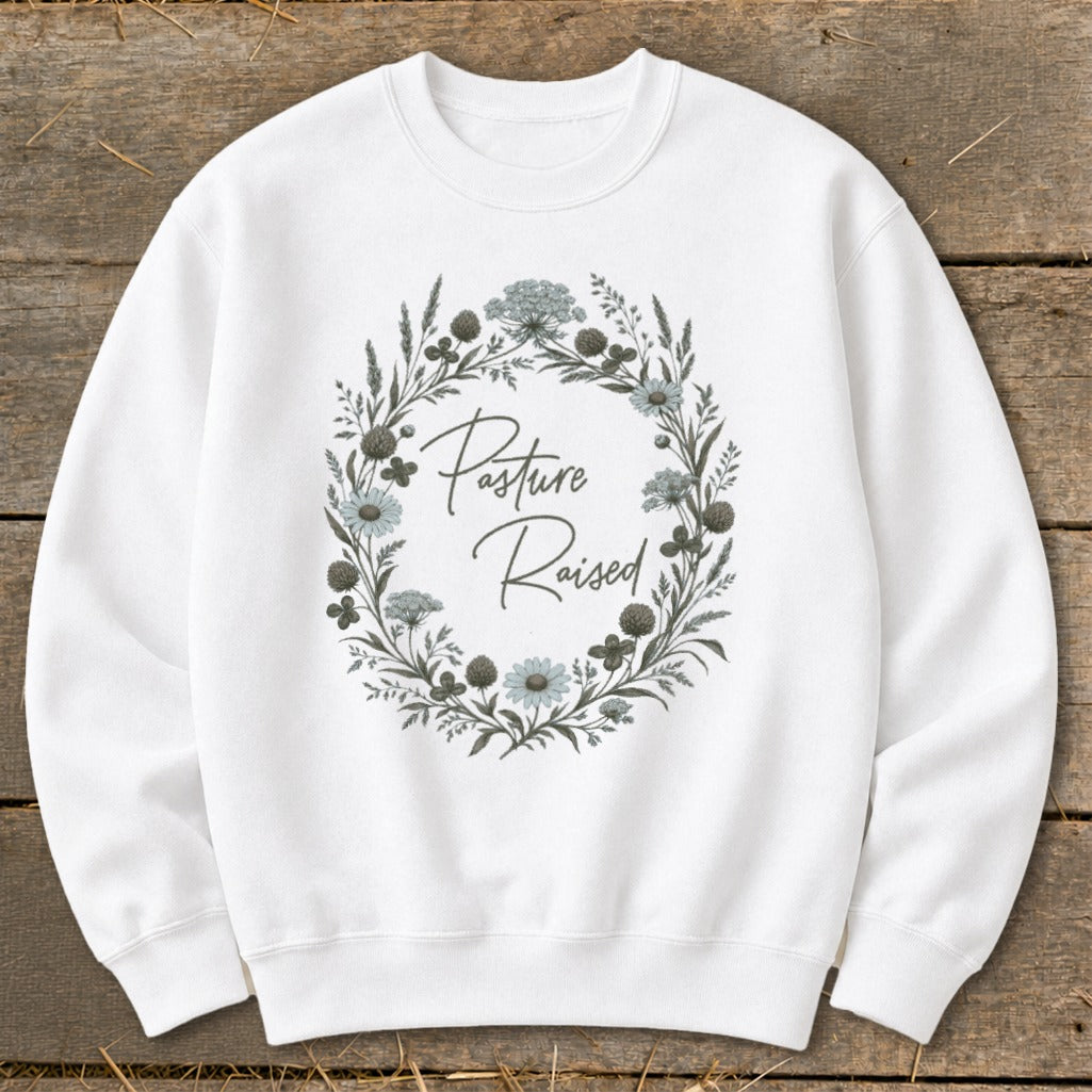 White sweatshirt with "Pasture Raised" text inside a floral wreath graphic.