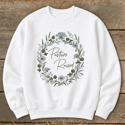 White sweatshirt with "Pasture Raised" text inside a floral wreath graphic.