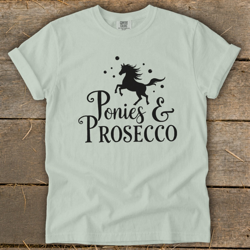Light green t-shirt with black graphic of a galloping horse and text "Ponies & Prosecco".