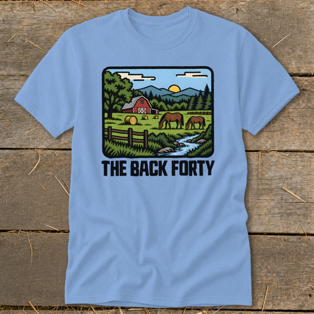 A light blue t-shirt featuring a rustic landscape graphic with a red barn, horses, and the text The Back Forty.