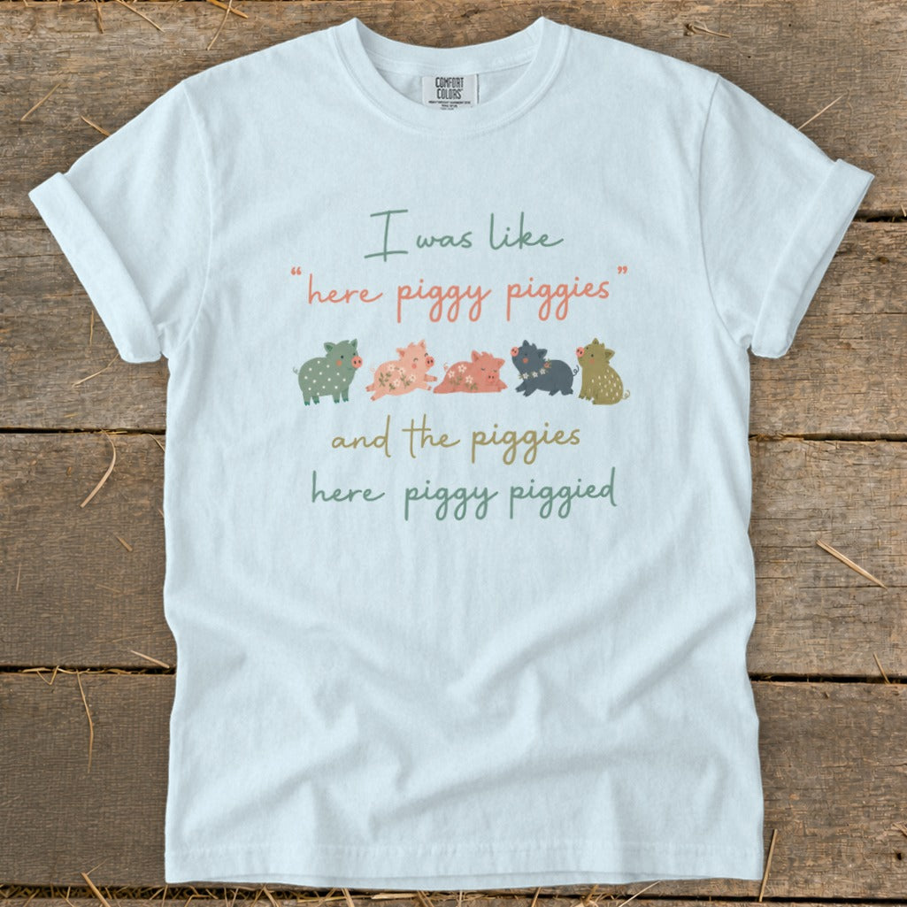 White t-shirt with "I was like 'here piggy piggies' and the piggies here piggy piggied" and cartoon pigs.