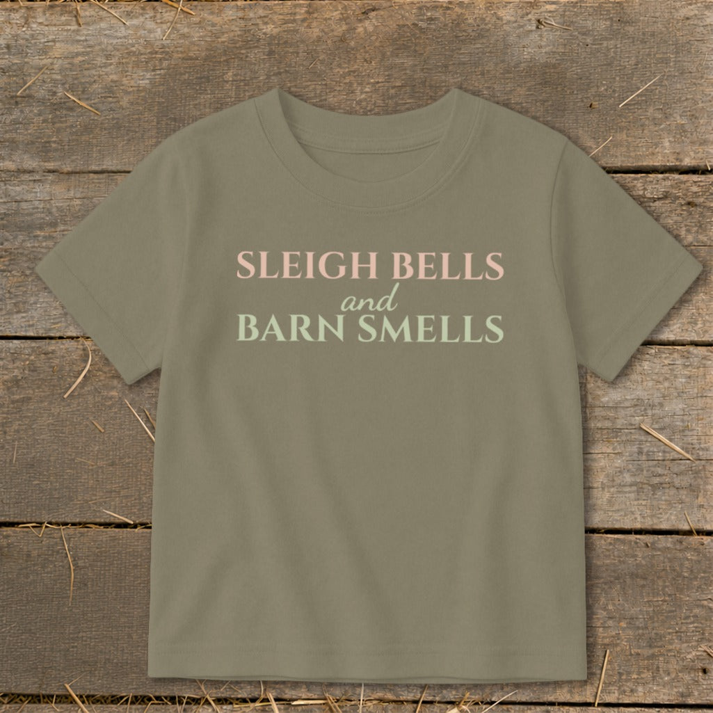 Tan t-shirt with "Sleigh Bells and Barn Smells" text in pink and green.