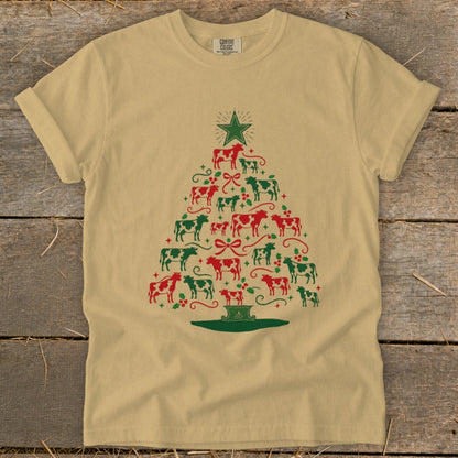 Tan t-shirt with a Christmas tree made of red and green cows, bows, and holly.
