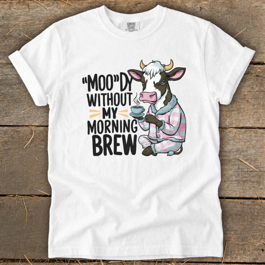 White t-shirt with cow in pajamas holding coffee, text: "MOO"DY WITHOUT MY MORNING BREW.