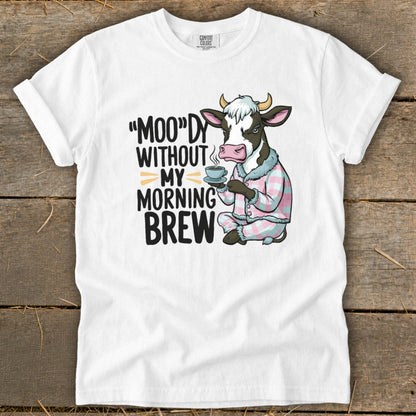 White t-shirt with cow in pajamas holding coffee, text: "MOO"DY WITHOUT MY MORNING BREW.